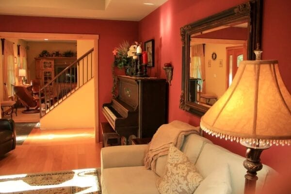 A living room with a couch, piano and mirror.